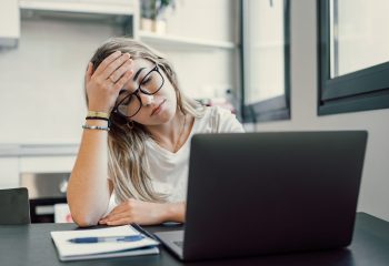 Stressed tired woman in pain having strong terrible headache attack after computer laptop study, fatigued exhausted girl suffering from chronic migraine massaging temples to relieve head ache tension